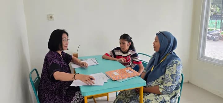 Psikolog berbincang dengan seorang ibu dan anaknya di meja kecil