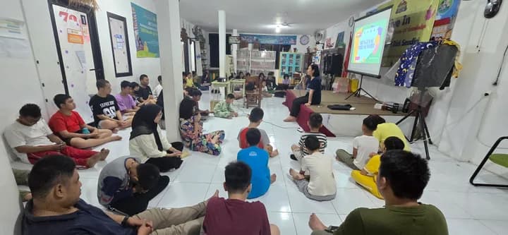 Anak-anak duduk di lantai aula mengikuti kegiatan bersama